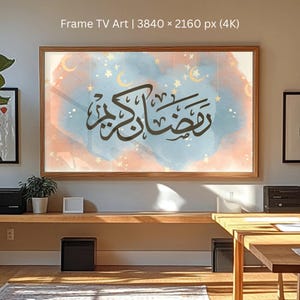 Puede incluir: Una obra de arte digital enmarcada con un fondo de acuarela en tonos de azul, melocotón y dorado. La obra presenta caligrafía árabe y elementos celestiales como lunas y estrellas. El marco es de madera.