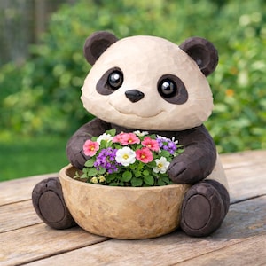 May include: A carved panda bear planter holding a bowl of colorful flowers. The panda has a cream-colored face and body with black accents on the ears, eyes, and paws. The flowers include pink, white, and purple blooms, creating a cheerful garden accent.