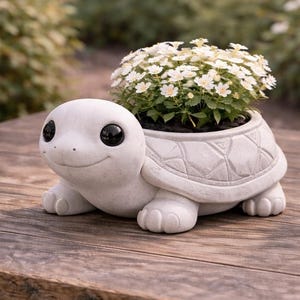 May include: A white turtle-shaped planter with a smiling face and large black eyes. The turtle's shell is textured, and it holds a cluster of small white flowers. The planter sits on a wooden surface, perfect for a garden or patio.