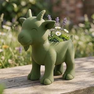 Puede incluir: Una maceta verde con forma de cabra llena de lavanda y margaritas. La maceta tiene una cara sonriente y está hecha de un material sólido. La maceta de cabra es un artículo decorativo para jardines y patios.