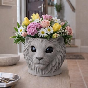 May include: A gray lion-shaped planter filled with a vibrant arrangement of flowers. The flowers include yellow tulips, pink roses, white daisies, and pink hydrangeas. The planter is made of concrete and sits on a wooden table.