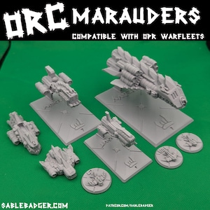 Könnte beinhalten: Eine Sammlung grauer Miniatur-Raumschiffmodelle, in verschiedenen Größen und Designs, auf grauen Sockeln präsentiert. Der Text "ORC MARAUDERS" und "COMPATIBLE WITH OPR WARFLEETS" sind sichtbar. Der Hintergrund ist grün.