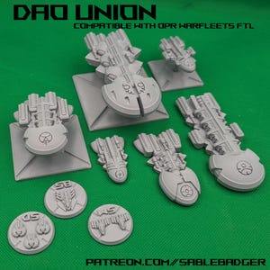 May include: A collection of gray miniature spaceship models and tokens. The models vary in size and design, with intricate details. The text "DAO UNION" and "COMPATIBLE WITH OPR WARFLEETS FTL" is visible at the top. The bottom of the image displays "PATREON.COM//SABLEBADGER".