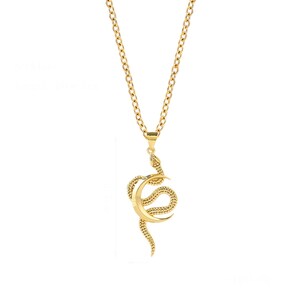 May include: A gold chain necklace with a pendant featuring a snake wrapped around a crescent moon.