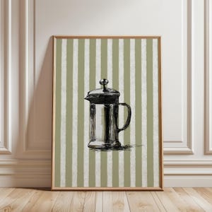 May include: A framed wall art print featuring a black ink sketch of a French press coffee maker centered against a background of vertical sage green and white stripes. The illustration uses loose, expressive lines to define the coffee press.