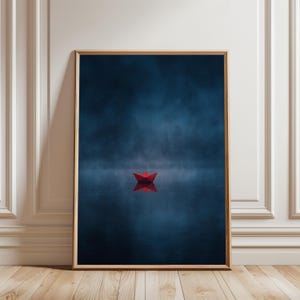 May include: A framed art print featuring a red paper boat floating on a dark blue body of water. The water reflects the boat, and a misty fog fills the background. The artwork is displayed in a wooden frame.