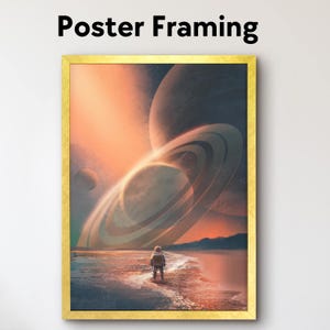 May include: A framed art print with a gold border, featuring a surreal landscape with a lone astronaut on a beach, facing a planet with large rings. The sky is a blend of orange and purple hues, with the text "Poster Framing" at the top.