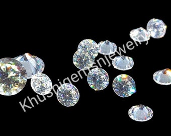 May include: A collection of clear, round, faceted gemstones, scattered on a black background. The gemstones have a rainbow iridescent effect.