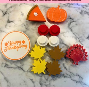 May include: A set of Thanksgiving-themed craft supplies, including a pumpkin, a slice of pie, a turkey, maple leaves, and a sign that says "Happy Thanksgiving".