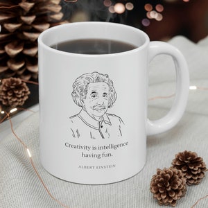 May include: White ceramic mug with a black and white illustration of Albert Einstein and the quote "Creativity is intelligence having fun. - Albert Einstein".