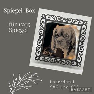 May include: Black laser cut frame with an ornate design, suitable for a 15x15 inch mirror. The frame has a mirror inside with a photo of a dog and the name "Lissy" inscribed in gold lettering. The text "Spiegel-Box für 15x15 Spiegel" is visible in the top left corner. The text "LaserdDatei SVG und XCS BAZAART" is visible in the bottom right corner.