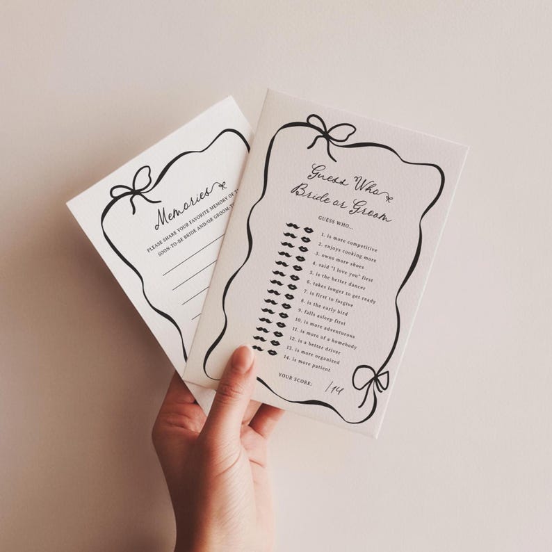 Pu&ograve; includere: Due biglietti bianchi con scritte nere e bordi decorativi. Un biglietto recita "Memories" e l'altro "Guess Who Bride or Groom". Il biglietto "Guess Who" ha un elenco di domande. I biglietti sono tenuti da una mano.
