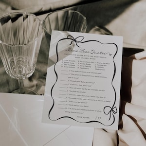 Pu&ograve; includere: Un biglietto bianco con il testo "Movie Love Quotes" e un gioco di abbinamento. Due bicchieri di vino trasparenti sono sullo sfondo. Il gioco include citazioni di film e titoli di film da abbinare. Il punteggio &egrave; 1/11.