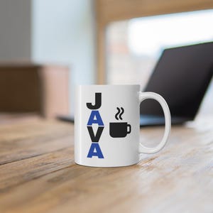 Pu&ograve; includere: Tazza in ceramica bianca con la scritta "JAVA" in lettere nere e blu. Un'icona di tazza di caff&egrave; nera con vapore &egrave; accanto alla parola. La tazza &egrave; su una superficie di legno, con un laptop sullo sfondo.