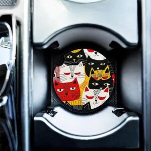 May include: A colorful coaster featuring a pattern of black, white, red, and yellow cats. The cats are arranged in a circular pattern and have different facial expressions.