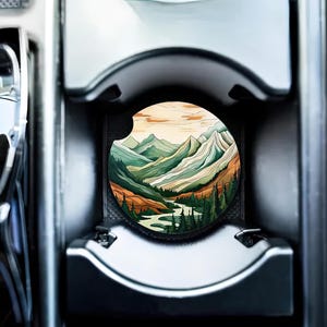 May include: A round coaster with a colorful illustration of a mountain range with a river winding through it. The mountains are green, brown, and yellow, and the river is blue. The coaster is made of a durable material and is perfect for protecting your furniture from spills.