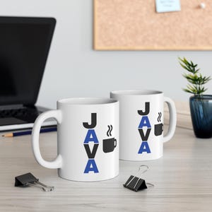 Pu&ograve; includere: Due tazze da caff&egrave; in ceramica bianca con la parola "JAVA" stampata verticalmente in nero e blu. Una grafica di tazza da caff&egrave; nera con vapore &egrave; accanto alla parola. Le tazze sono su una superficie chiara.