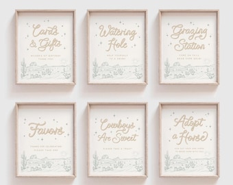 Op de afbeelding: Zes ingelijste borden met lichte houten randen met woestijnlandschapillustraties in saliegroen. De borden tonen tekst in goudkleurig schrift: Cards & Gifts, Watering Hole, Grazing Station, Favors, Cowboys Are Sweet en Adopt a Horse.