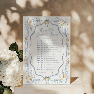Puede incluir: Una tarjeta de juego de boda rectangular titulada Guess Who Bride or Groom con una lista de 14 preguntas. La tarjeta presenta un borde decorativo azul claro con ilustraciones de cítricos amarillos, hojas verdes y cintas azules, además de iconos de bigotes y labios.