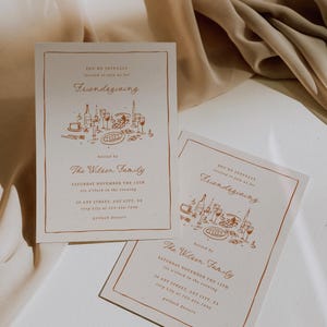 K&ouml;nnte beinhalten: Zwei cremefarbene Friendsgiving-Einladungskarten mit braunem Rand und Text. Die Einladungen enthalten den Text "You're joyfully invited to join us for Friendsgiving" und "The Wilson Family". Die Einladungen liegen auf einer beigen Oberfl&auml;che.