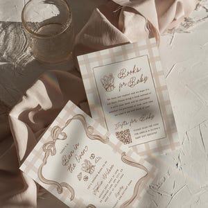 K&ouml;nnte beinhalten: Zwei rechteckige Papierkarten mit beigefarbenem und wei&szlig;em Vichy-Muster. Eine Karte tr&auml;gt die Aufschrift 'There's a Bun in the Oven' mit Schleifenrand und Details zur Babyparty. Die andere Karte zeigt 'Books for Baby' und einen QR-Code.