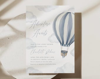 May include: A baby shower invitation card featuring a watercolour illustration of a blue and white striped hot air balloon floating among soft grey clouds. The text reads Adventure Awaits, Join us for a baby shower, honouring mommy-to-be, Charlotte Robins, April the 26th from 1-4pm, 75 Cliff Drive, Malibu, California, RSVP to Kayla at 123.456.7890, Registry at Babylist.com/babyrobins.
