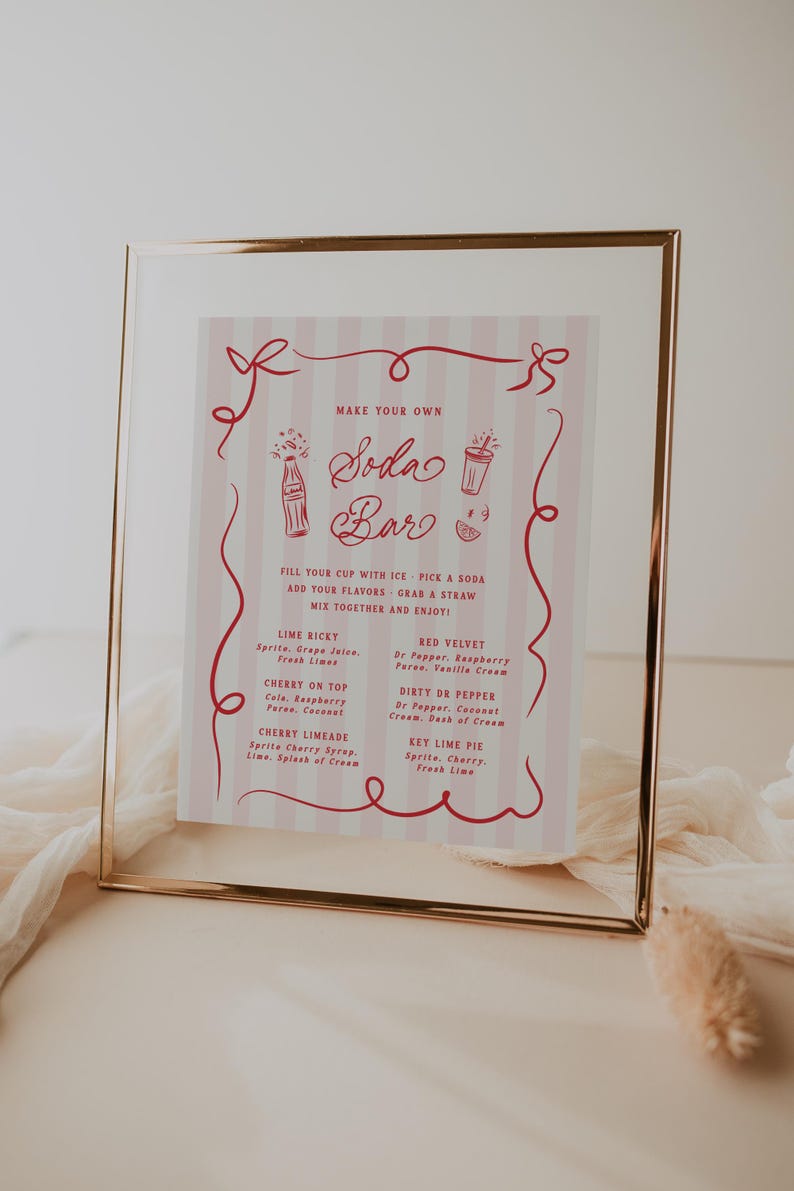 May include: A framed pink and white sign with a gold border, advertising a soda bar. The sign features red text and illustrations, including soda bottles and glasses. It lists soda flavor combinations like Lime Ricky and Cherry Limeade.