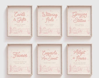 Op de afbeelding: Zes lichtroze ingelijste borden met woestijnillustraties en tekst waaronder Cards & Gifts, Watering Hole, Grazing Station, Favors, Cowgirls Are Sweet en Adopt a Horse. Elk bord toont een westelijk landschap met cactussen.