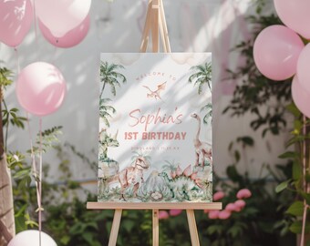 May include: A rectangular birthday welcome sign on a wooden easel featuring watercolor illustrations of dinosaurs, palm trees, and clouds. The text reads Welcome to Sophia's 1st Birthday Diroland 11.25.XX in pink and brown lettering.