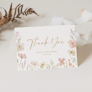 May include: A white thank you card with a floral design and gold lettering. The text reads "Thank You" and "Olivia's Baby Shower 03.25.XX".