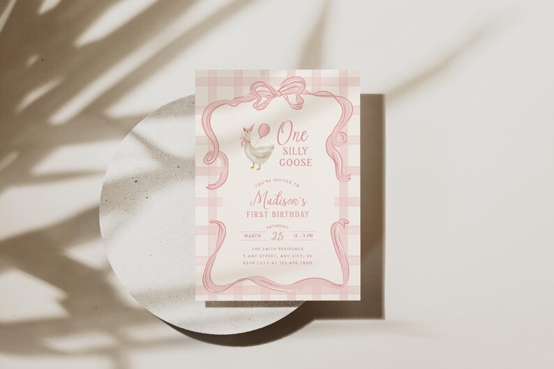 May include: A pink and white invitation card with the text "One Silly Goose" and "Madison's First Birthday." The card features a cartoon goose holding a balloon and is decorated with pink ribbons and a plaid background.