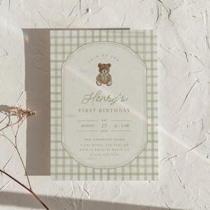 May include: A first birthday invitation with a teddy bear illustration. The invitation features the text "Henry's First Birthday" and event details, including the date, time, and location, set against a green gingham pattern.