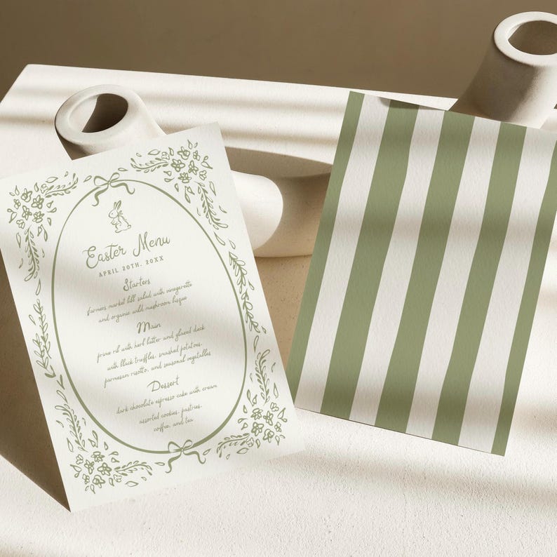 Pu&ograve; includere: Un biglietto bianco con un bordo floreale verde e una cornice ovale. Il testo all'interno della cornice recita "Easter Menu" con la data "April 20th, 20XX". Il menu elenca "Starters", "Main" e "Dessert".