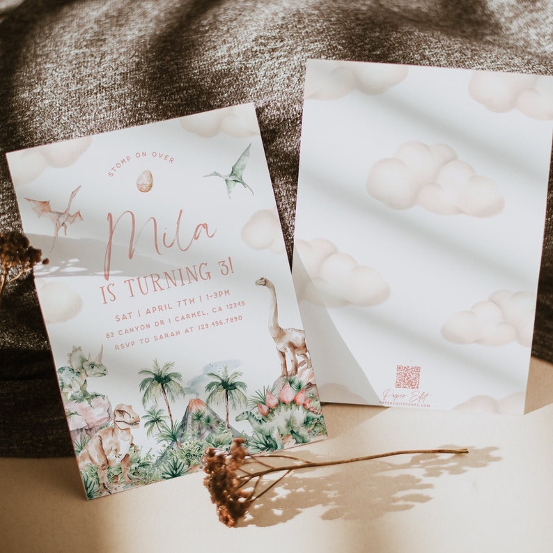 May include: A pink and green dinosaur-themed birthday invitation for a girl turning three. The invitation features a watercolor illustration of dinosaurs, palm trees, and a volcano. The text reads "Stomp on Over Mila is Turning 3!" with the date, time, and RSVP information.