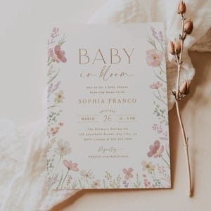 May include: A baby shower invitation with a floral design. The invitation is for Sophia Franco and is set for Saturday, March 26th from 12-3 PM at The Biltmore Restaurant. The invitation includes the text "Baby in Bloom" and a floral design with pink and purple flowers.