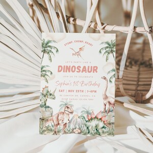 May include: A pink and green dinosaur-themed first birthday party invitation with a watercolour illustration of dinosaurs and palm trees. The text reads "Stomp, Chomp, Roar! Let's party like a Dinosaur. Join us to celebrate Sophia's 1st Birthday. Sat Nov 25th | 1-4pm. 82 Canyon Dr Carmel, CA. RSVP Sarah 123.456.7890."