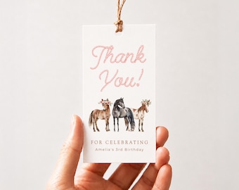 May include: A rectangular white gift tag with a brown string loop. The text Thank You! is printed in pink rope-style font above an illustration of three horses wearing floral crowns. Below the horses, the text reads FOR CELEBRATING Amelia's 3rd Birthday.