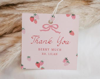 May include: A square light pink gift tag featuring a pattern of small red and pink strawberries. The tag displays a pink bow illustration, the text Thank You, BERRY MUCH, and XO. LILAH in red font, with a white string attached through a hole.