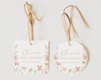 Op de afbeelding: Twee witte papieren cadeaulabels, een vierkant en een rond, elk met een lichtbruin leren koord. De labels tonen bloemillustraties in roze, groen en lavendel, met de tekst Olivia's BABY SHOWER thanks for celebrating!