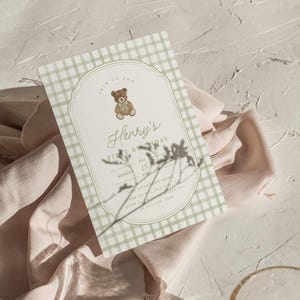 May include: A baby's first birthday invitation with a gingham pattern in light green and white. The invitation features a teddy bear illustration and the text "Henry's First Birthday" with the date August 15, 2021.