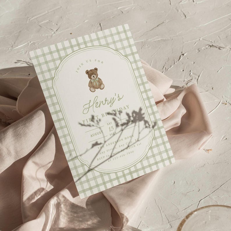 May include: A baby's first birthday invitation with a gingham pattern in light green and white. The invitation features a teddy bear illustration and the text "Henry's First Birthday" with the date August 15, 2021.