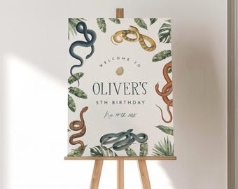 May include: A rectangular birthday welcome sign on a wooden easel featuring illustrations of various snakes and tropical leaves. The text reads: Welcome to Oliver's 5th Birthday Nov 10th 2024, with a small egg icon centred above the name.