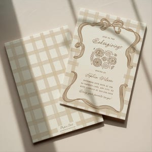 May include: Two beige and white plaid invitations. One invitation features the text "Join us for Bakesgiving" with a decorative ribbon and illustrations of baked goods. The other invitation has a plaid pattern.