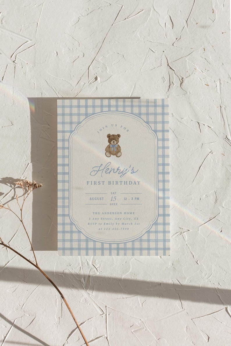May include: A rectangular birthday invitation card featuring a light blue and white gingham border. The center displays a brown teddy bear with a blue bow, the text Henry's FIRST BIRTHDAY, and event details including date, time, and location.