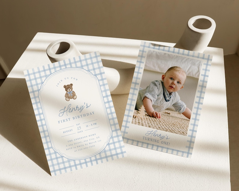 May include: Two rectangular birthday invitation cards featuring a light blue and white gingham pattern. One card displays a teddy bear illustration and text reading Henry's First Birthday, while the other shows a photograph of a child.