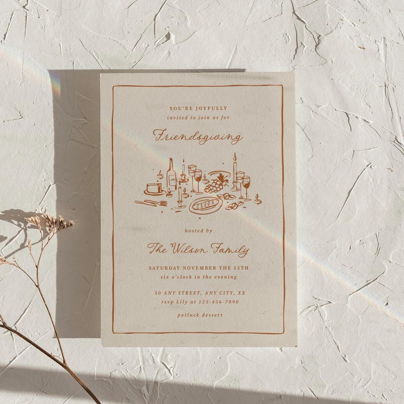K&ouml;nnte beinhalten: Eine beige Friendsgiving-Einladung mit braunem Rand und Text. Die Einladung enth&auml;lt die W&ouml;rter "Friendsgiving" und "The Wilson Family". Eine detaillierte Illustration einer Tischdekoration mit Speisen und Getr&auml;nken ist ebenfalls vorhanden.
