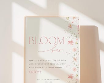 May include: A vertical rectangular sign with a light cream background featuring the pink text BLOOM BAR. The right side displays delicate pink floral illustrations. Text instructions read: MAKE A BOUQUET TO TAKE ON YOUR WAY, CHOOSE YOUR BLOOMS, WRAP WITH PAPER & TIE WITH RIBBON. ENJOY! WHITNEY'S BRIDAL SHOWER 05.12.XX.