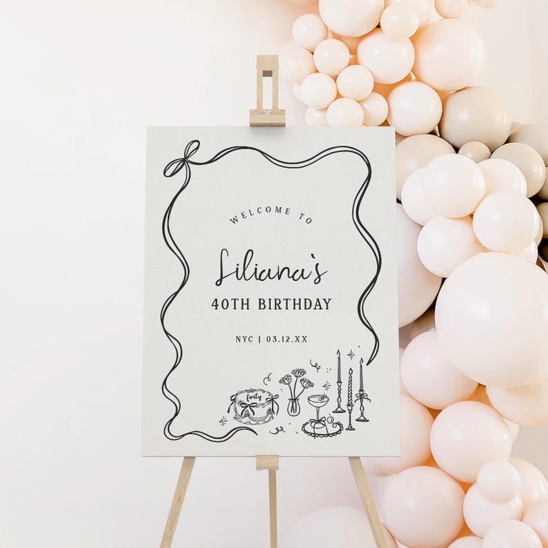 May include: A white sign on a wooden easel with the text "Welcome to Liliana's 40th Birthday" in black script. The sign includes decorative line art of a bow, ribbon, and birthday-themed illustrations. A balloon arch is in the background.