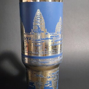 May include: A blue and gold stainless steel travel mug with a design of Angkor Wat, a temple complex in Cambodia.