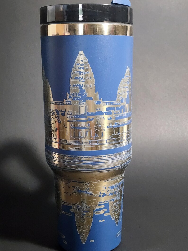 May include: A blue and gold stainless steel travel mug with a design of Angkor Wat, a temple complex in Cambodia.